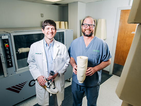 Conley Carr, M.D. (left) and Brian Mueller (right) with custom prostheses created in the UAB Orthotics and Prosthetics Lab.